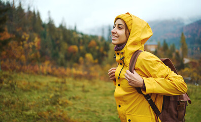 Portrait happy hiker girl in yellow wear and backpack traveling in mountains alone, into the wild adventure travel outdoor journey