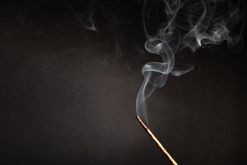 incense stick with smoke against black background