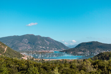 Fototapeta na wymiar Bright Vlicho bay view from hills of Lefkada island Katochori village, Ionian Islands, Greece. Boats, blue sea and sky surrounded by summer greenery