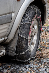 Detail of a chain on the front wheel of a car.
