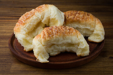 Freshly baked croissants on rustic plate on a dark wooden table. Delicious breakfast