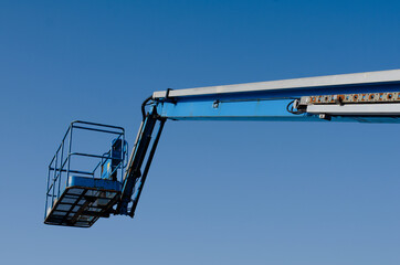 Telescopic boom lift raised up on blue sky background delivered to construction site ready to be used by steel frame erectors, roofers and painters  © Iryna