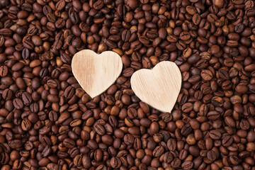 Macro photography of roasted brown coffee beans. A flat composition. Close-up, top view. Two wooden hearts. Love for coffee.