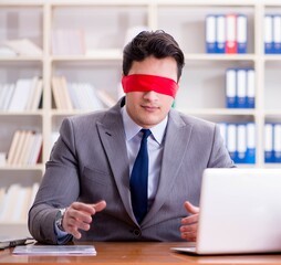 Blindfold businessman sitting at desk in office