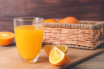 Glass with tasty orange juice on wooden background