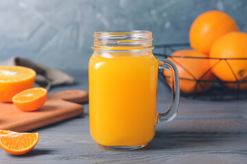 Mason jar with tasty citrus juice on color background