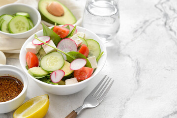 Plate with fresh salad on light background