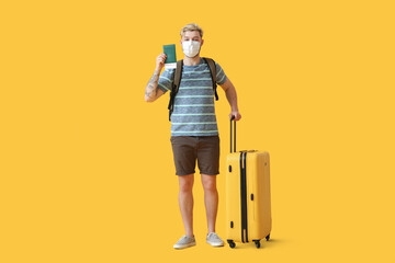 Male tourist in medical mask on color background