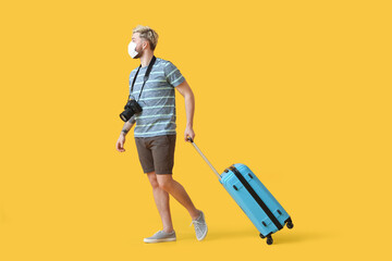 Male tourist in medical mask on color background