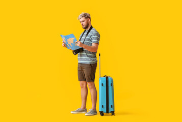 Male tourist with map on color background