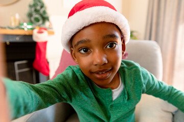 African american boy wearing santa hat and taking selfie at christmas time
