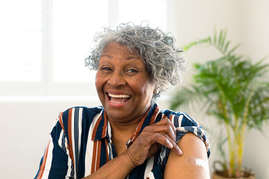 Happy senior african american woman with plaster on arm looking at camera after vaccination