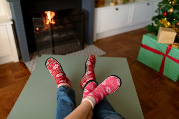 Feet of caucasian couple wearing christmas socks and sitting on sofa at christmas time