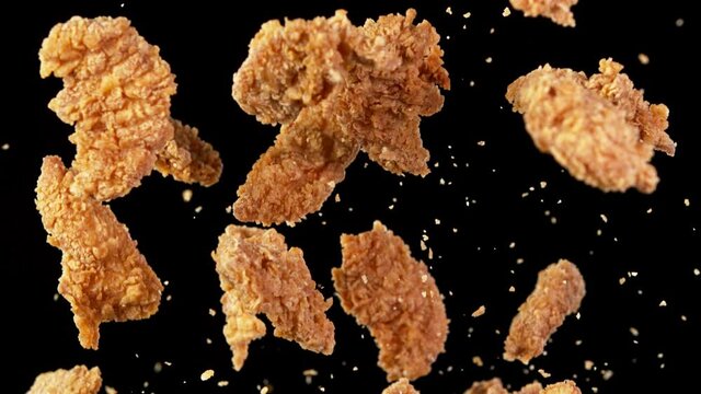 Super slow motion of flying fried chicken wings on black background. Filmed on high speed cinema camera, 1000fps. Speed ramp effect.