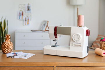 Tailor's workplace with sewing machine and sketches in atelier