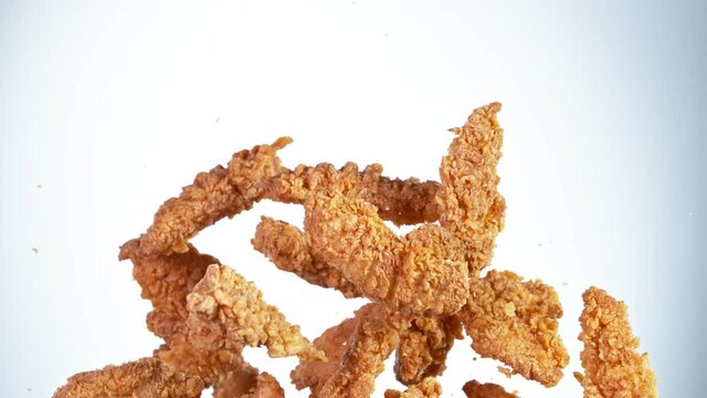 Super slow motion of flying fried chicken stripes on white background. Filmed on high speed cinema camera, 1000fps.
