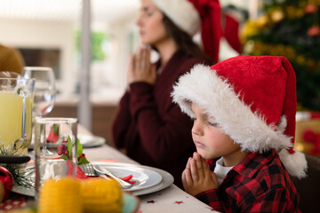 Caucasian boy and his mother praying together at christmas table