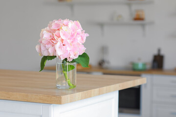 Vase with hydrangea flowers on table in kitchen
