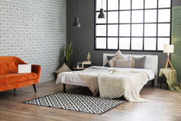 Interior of modern bedroom with big window and comfortable furniture