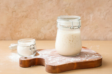 Glass jar with fresh sourdough on table