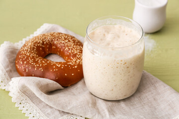 Jar with fresh sourdough and bagel on green wooden background