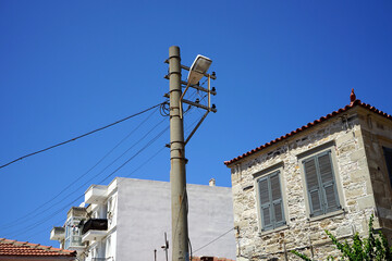 Alter Stromleitungsmast mit Straßenbeleuchtung vor blauem Himmel im Sommer bei Sonnenschein in...