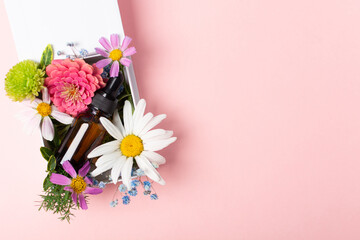 Cosmetic oil or perfume or medication in brown glass with pipette and flowers