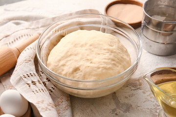 Bowl with fresh dough on light background