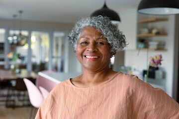 Happy african american senior woman standing standing in kitchen and looking at camera