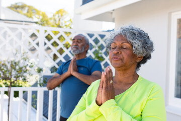 Focused african american senior couple practicing yoga in garden - Powered by Adobe