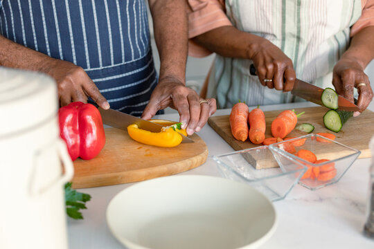 Midsection of arfican american senior couple cutting vegetables and preparing meal together