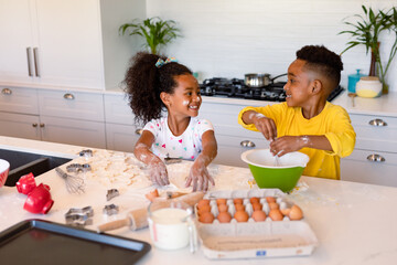 Happy african american siblings baking in kitchen