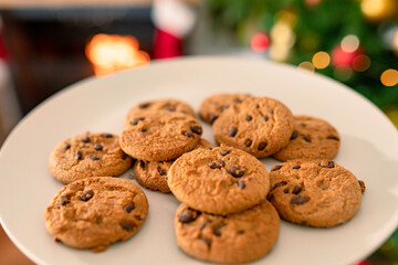 Chocolate cookies lying on plate, christmas decorations in background