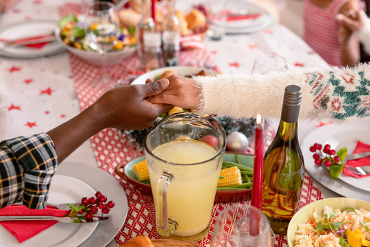 African american mother and daughter holding hands over christmas table