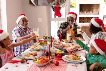 Happy multi generation family wearing santa hats, having christmas meal