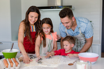 Happy caucasian family baking together, making cookies in kitchen
