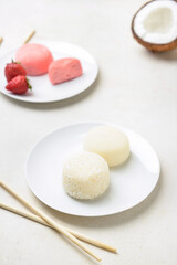 Plates with tasty Japanese mochi and chopsticks on light background