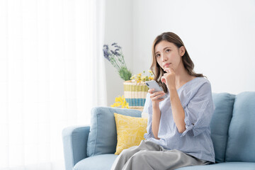 スマホを見ながら考え事をする若い女性