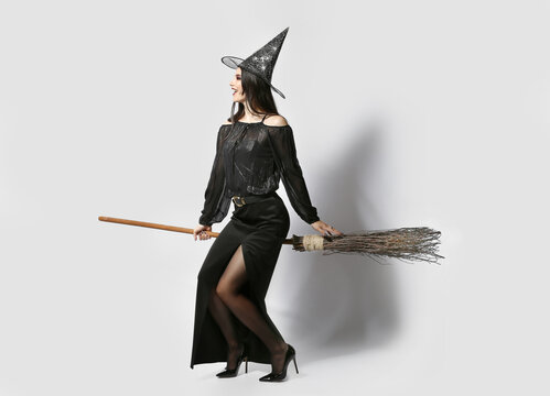 Young witch with broom on light background