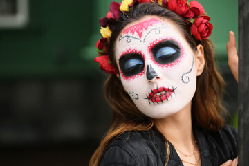 Young woman with painted skull on her face outdoors. Celebration of Mexico's Day of the Dead (El Dia de Muertos)