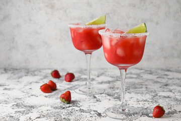 Glasses of tasty strawberry margarita on grunge background