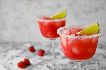Glasses of tasty strawberry margarita on grunge background, closeup