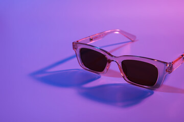 Stylish female sunglasses on color background