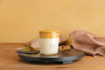 Glass of tasty dalgona hojicha latte, chasen and powder on table