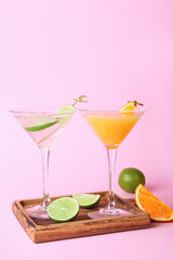 Glasses of gin and tonic on color background