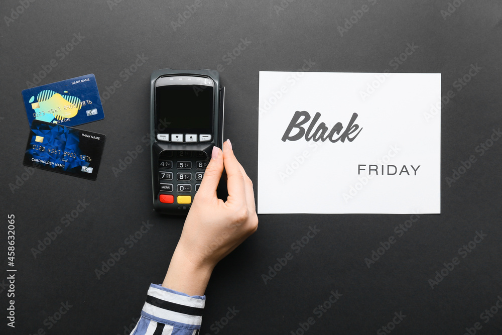 Wall mural Female hand, card with text BLACK FRIDAY, payment terminal and credit cards on dark background