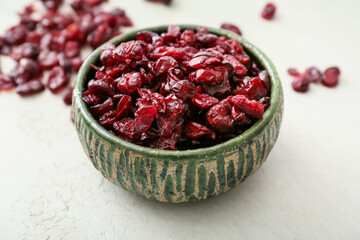 Bowl with tasty dried cranberries on light background, closeup