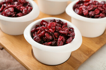 Bowls with tasty dried cranberries on table, closeup