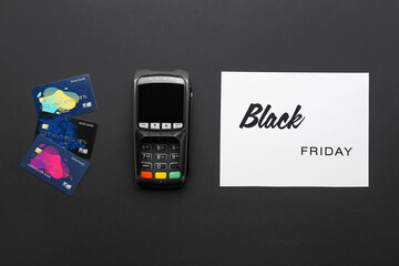 Card with text BLACK FRIDAY, payment terminal and credit cards on dark background