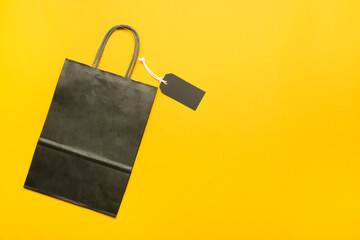 Shopping bag and tag on color background. Black Friday sale